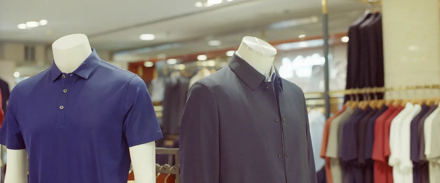 Polo shirts and a jacket on mannequins in a clothing store