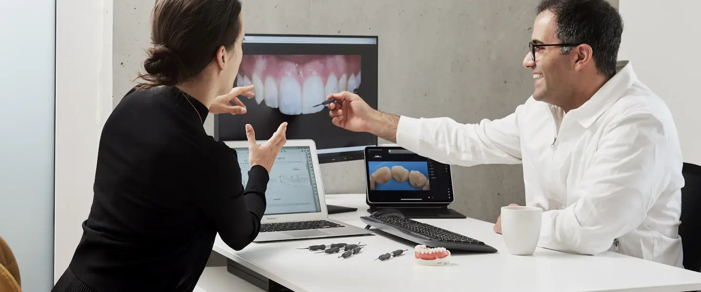 A dentist and a visitor going over dental scans on screen