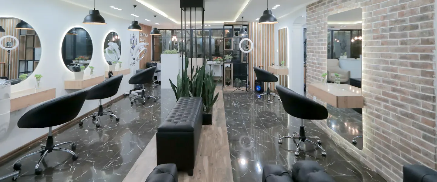 A modern hair salon with black chairs and round mirrors